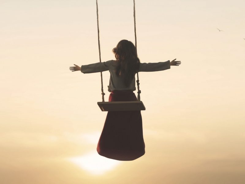 special contact between nature and a woman with open arms on a swing